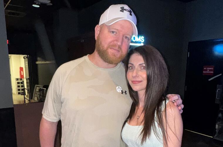 A man and women pose standing in a nightclub.
