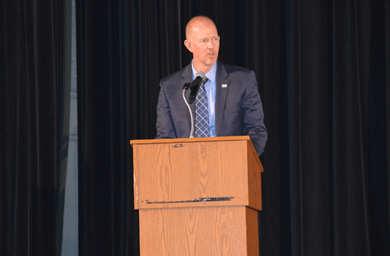 A man stands in front of a podium on a stage.