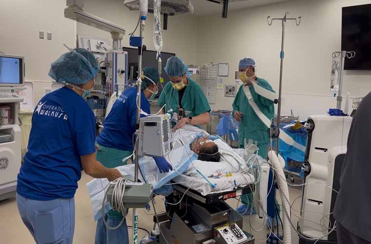 A person undergoing surgery. The person is on the operating table surrounded by medical personnel.