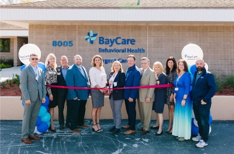 Group of individuals participating in a ribbon-cutting ceremony outside the BayCare Behavioral Health center.