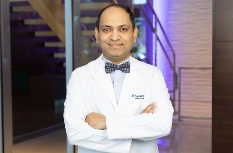 Dr. Subhasis Misra, pictured in a smiling headshot, dons a white lab coat over a blue button-down shirt complemented by a stylish bow tie.