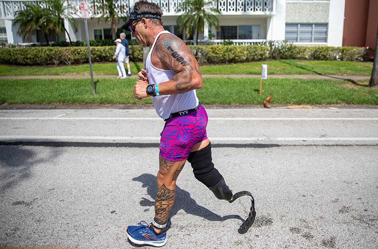 An adaptive athlete runs through the streets during a race. 