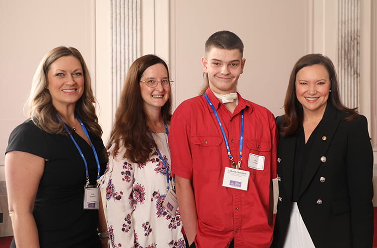 Three women and a teen boy smile smiling.