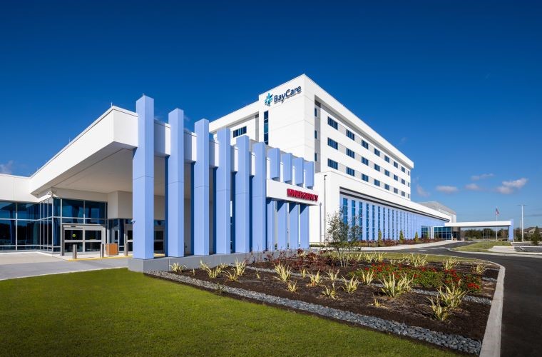 Exterior view of BayCare Hospital Wesley Chapel on a sunny day, featuring modern architectural design with large vertical columns and landscaped grounds.