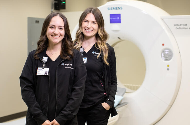 Two female BayCare team members stand by an MRI machine.