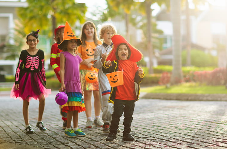 A group of children dressed in Halloween costumes standing together. 