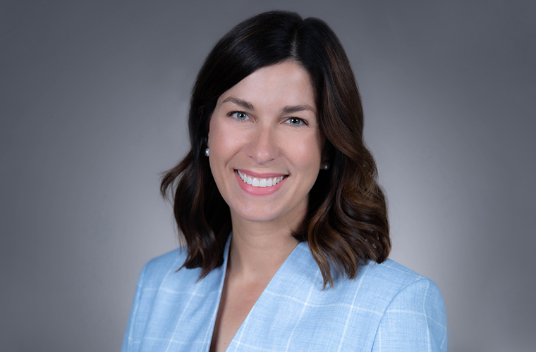 A headshot of a woman with shoulder-length brown hair wearing a light blue jacket.  