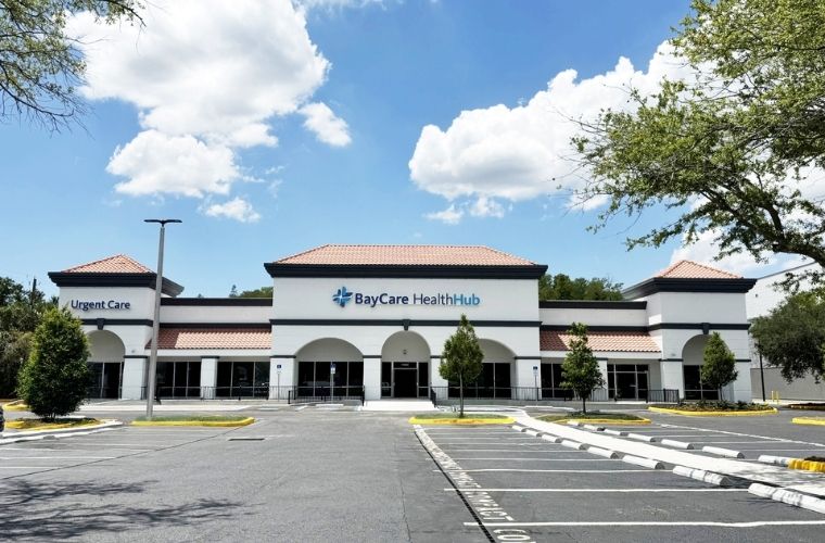 Exterior of BayCare HealthHub (Carrollwood) with Urgent Care entrance, parking spaces and BayCare HealthHub signage.