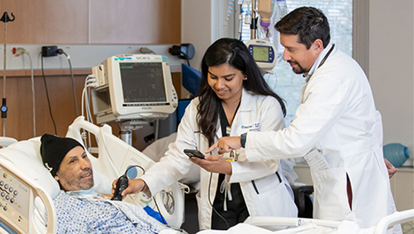 A faculty member helps a resident interpret the results of a test she is performing on a mock patient.