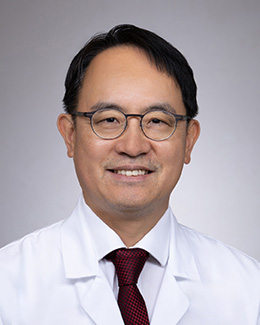 Headshot of Younqan Kim, PhD, MD in a lab coat