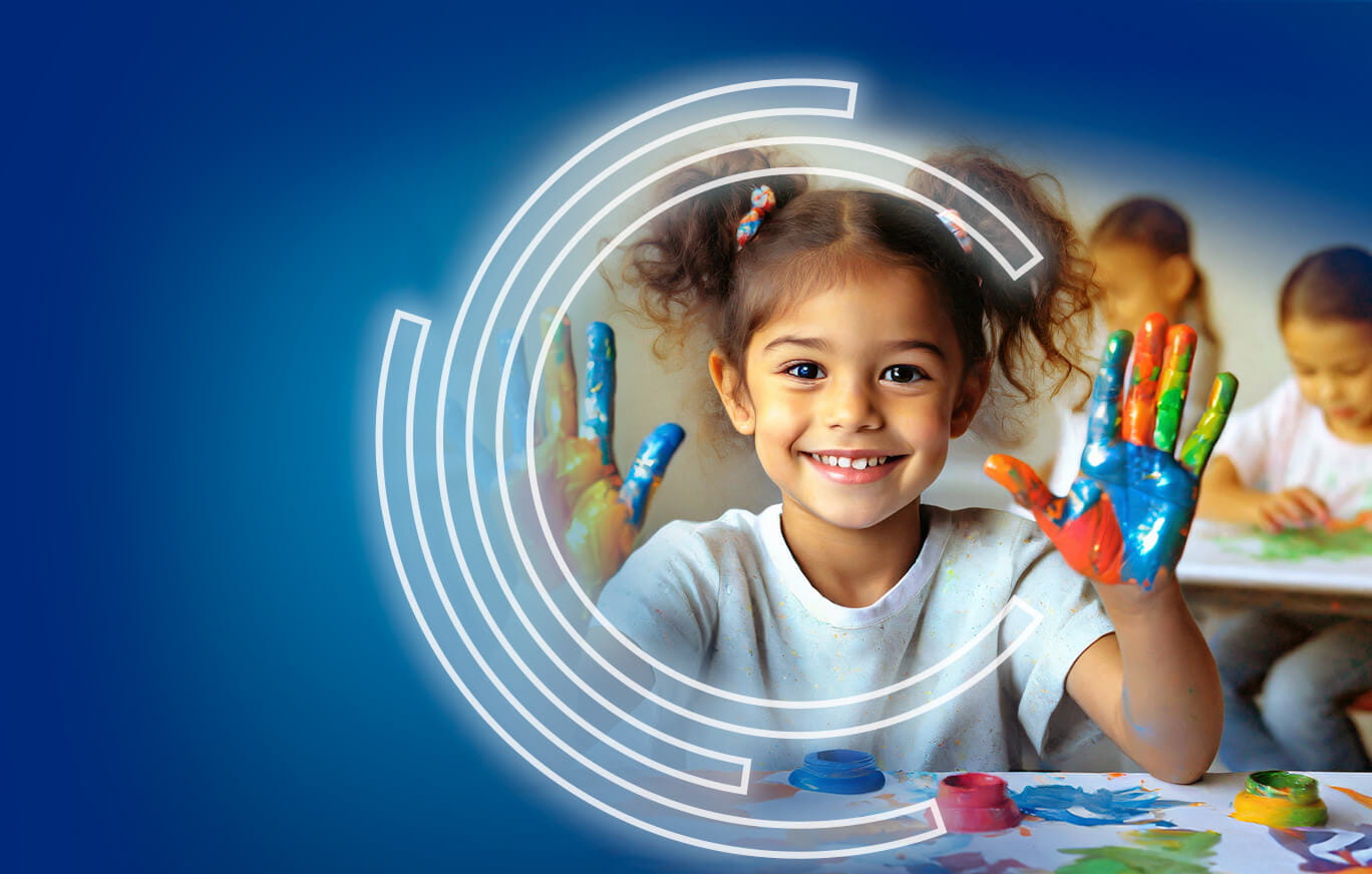 A young girl in a classroom setting smiling with paint on her hands, surrounded by the BayCare Effect logo
