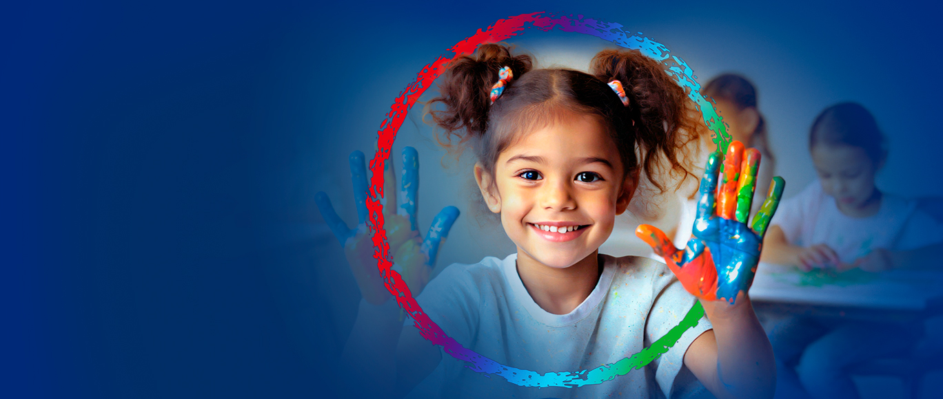 BayCare Kids Back To School A young girl in a classroom setting smiling with paint on her hands, surrounded by the BayCare Effect logo