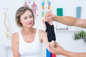 A doctor examines his female patient's wrist in a medical office.