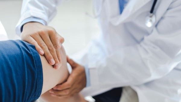 A doctor testing knee movement on a patient.