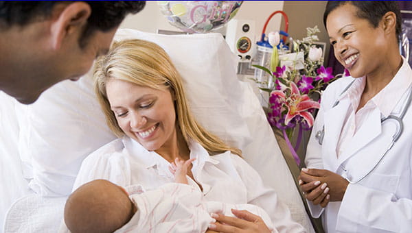A doctor visits with a mother, father and their newborn baby.