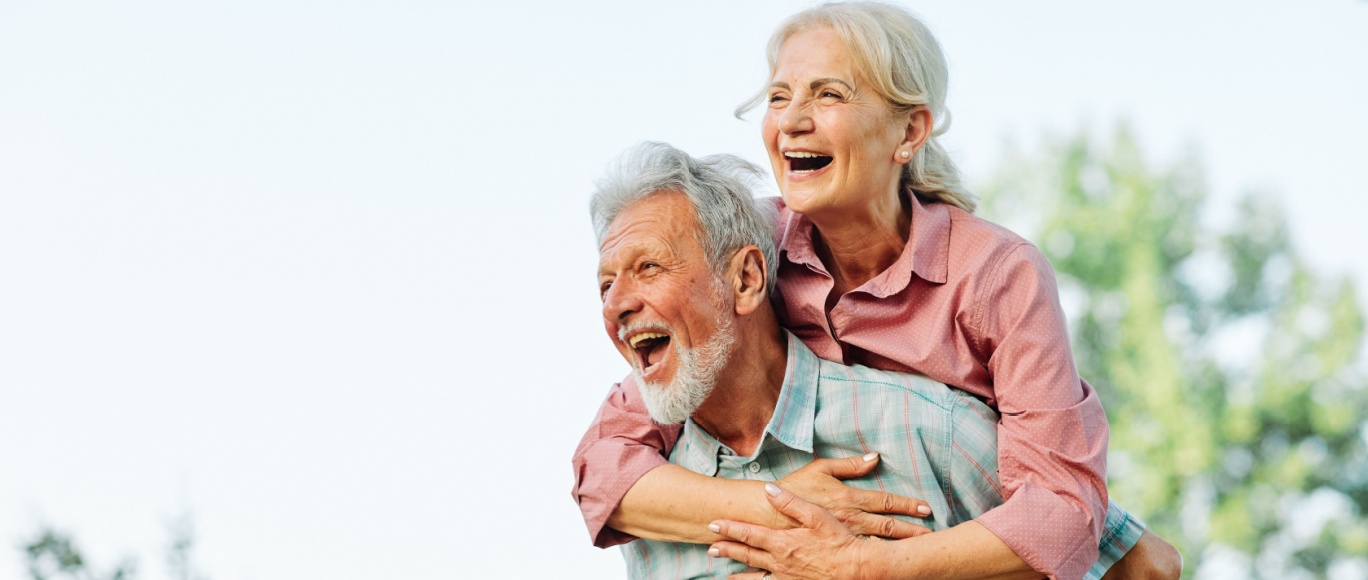 Grandpa piggy backing grandma, smiling and laughing