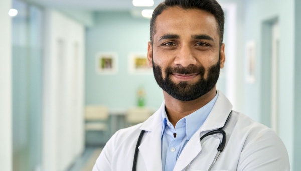 smiling male doctor wearing labcoat in hospital hallway
