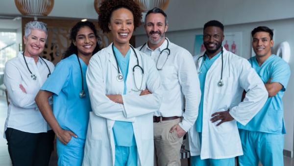 team of clinical professionals wearing scrubs and labcoats posing for group photo