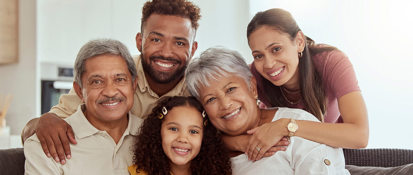 multigenerational family smiling while sitting on a couch.