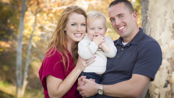 A husband and wife are outdoors with their toddler son.