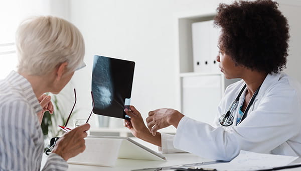 A physician shows a patient a breast scan image.