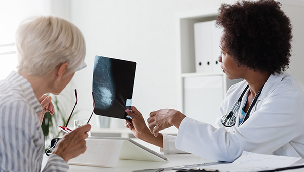 A physician shows a patient a breast scan image.