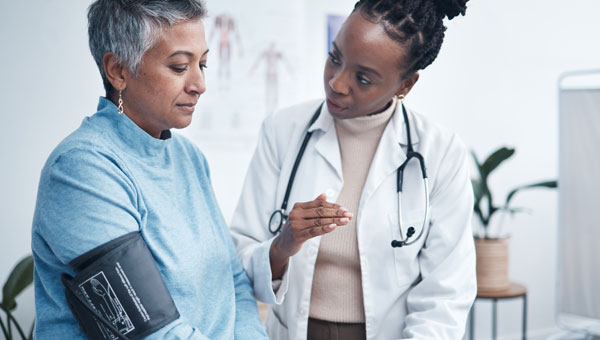 female doctor taking blood pressure cuff of female patient