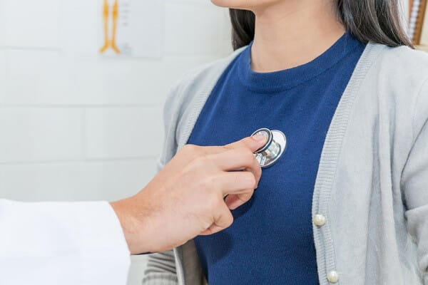 Close up of Doctor using stethoscope to exam heart and lungs of patient woman