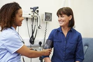 Nurse Taking Female Patient's Blood Pressure In Hospital