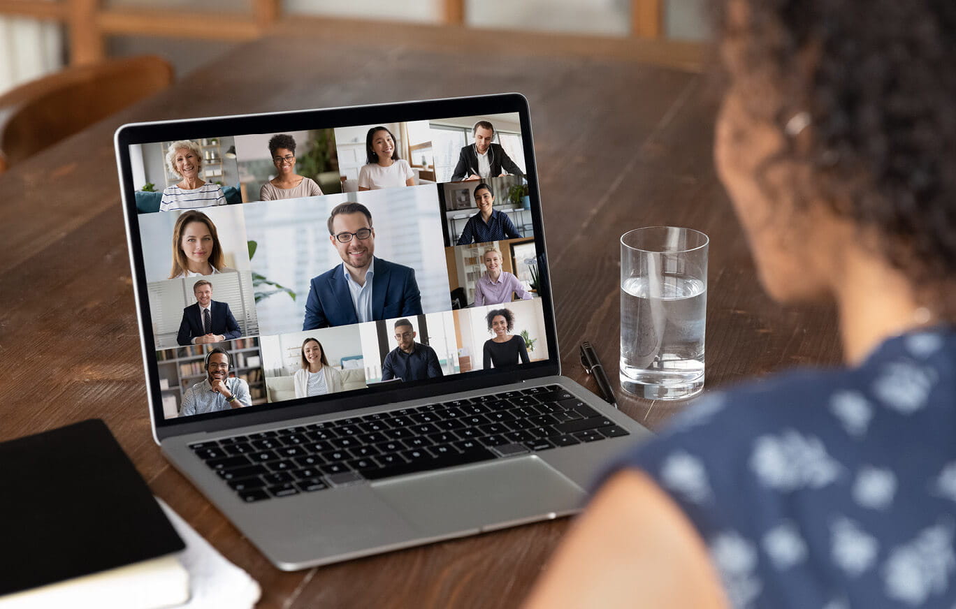 woman looking at labtop screen with numerous people on video call