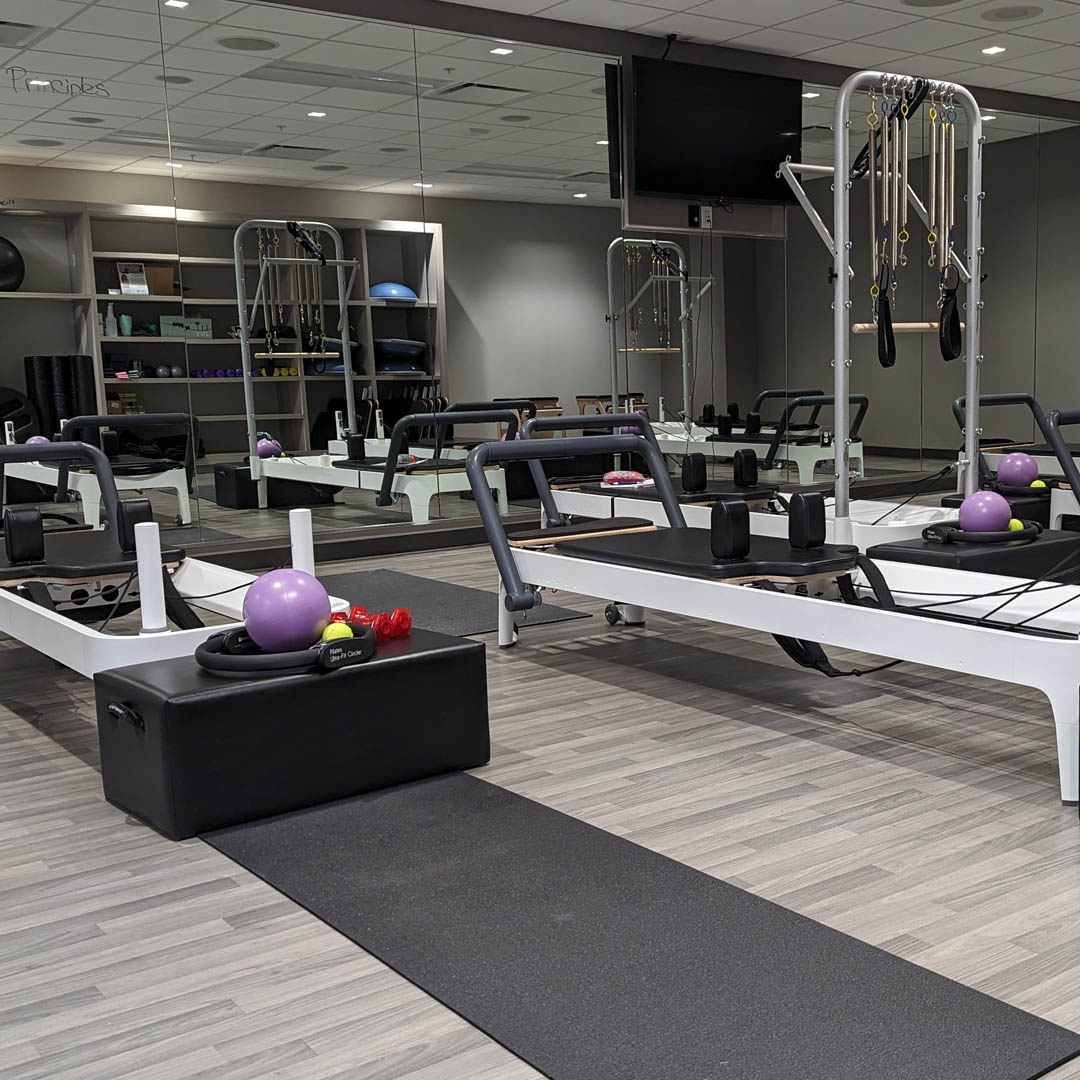 fitness center equipment neatly aligned against a wall of mirrors including weights and yoga mats