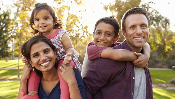 A father and mother with their young son and daughter in a park