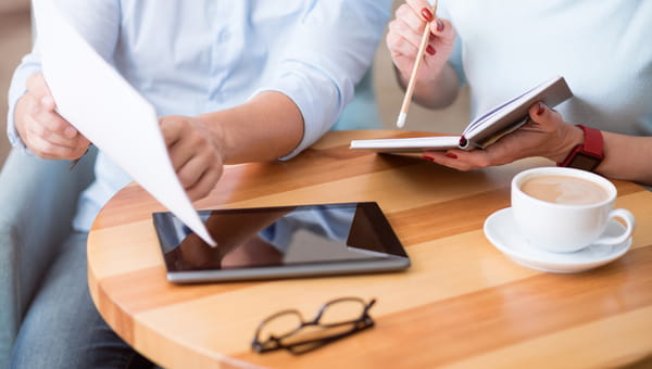 Cropped picture of colleagues holding paper and writing something down