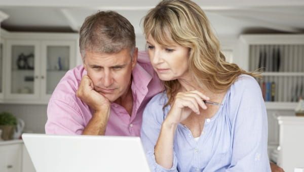 A man and woman looking at a laptop screen. 