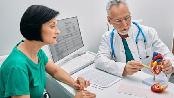 A physician inspects a heart model, emphasizing aortic stenosis, to illustrate its structure and potential health effects.