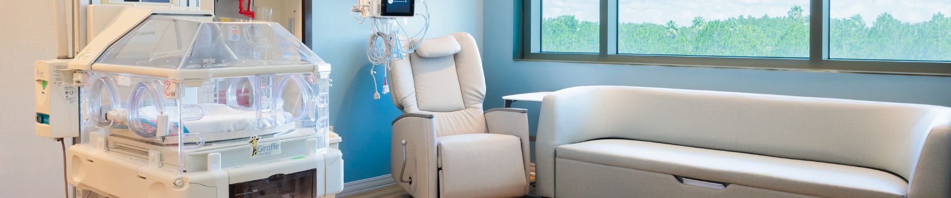 A hero image of a private NICU Room at the St Joseph's North Hospital, showing a chair, couch, and NICU Bed