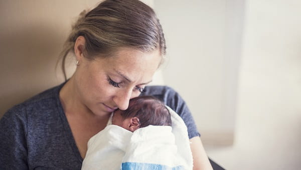 A mother is visiting her premature baby in the neonatal intensive care unit.