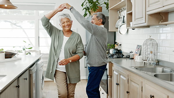 Senior couple dancing in a kitchen.