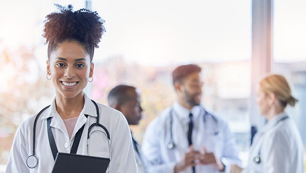 Femail doctor standing in front of a group of other doctors.