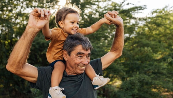 A smiling older man holds a child on his shoulders, representing family connections in the context of BayCare robotics surgery orthopedics.