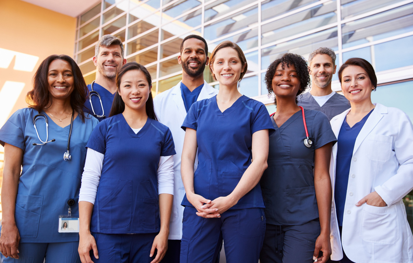 Joint Replacement Surgery at BayCare A group of diverse medical staff wearing blue scrubs standing in front of a medical building smiling.