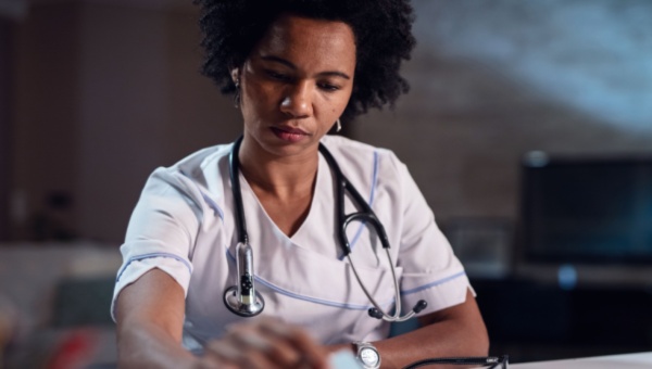 an African American physician sitting at a desk looking down at paperwork, looking focused 