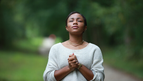a woman outside standing and praying on a road