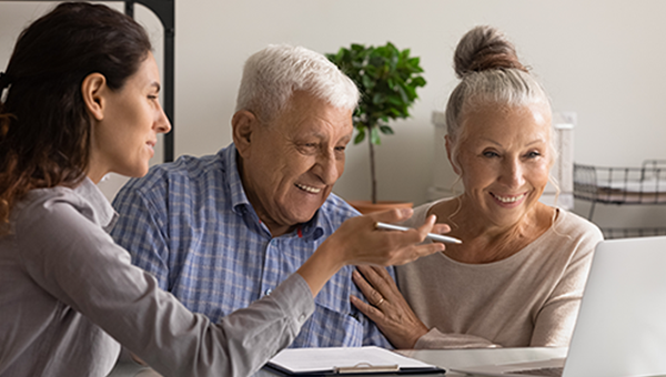 Woman consultant advises elderly spouses good medical life health insurance on a computer.