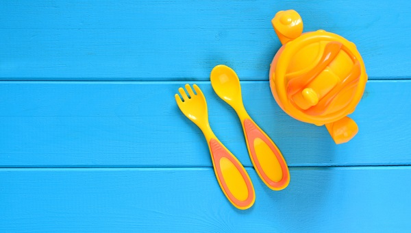Children fork, spoon and feeding bottle on a wooden table