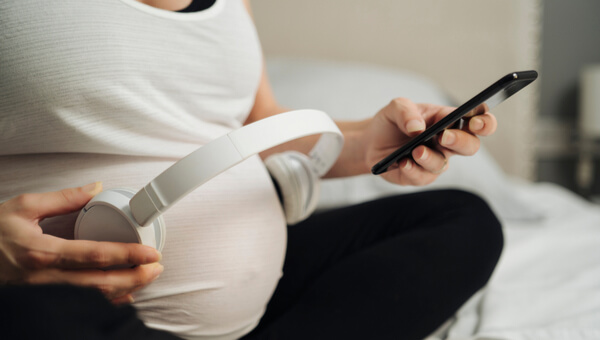 a woman holding a pair of headphones to her stomach