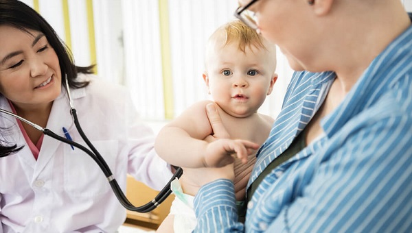 Cute Baby Being Examined By Doctor While Carrying By Mother