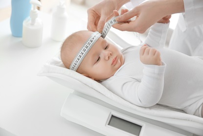Doctor examining baby on scales in room