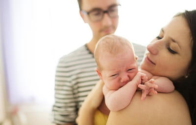 Young parents are holding their crying newborn girl at home