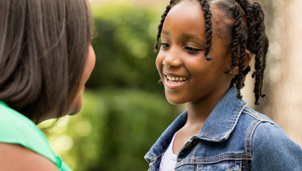 Young smiling girl speaking to an adult